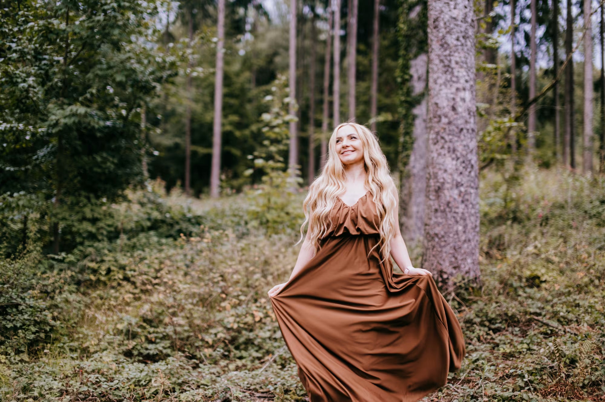 Woman in a long brown dress standing in a forest