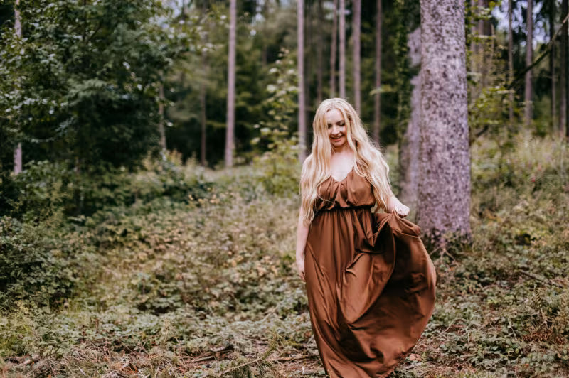 Woman in a long brown dress standing in a forest