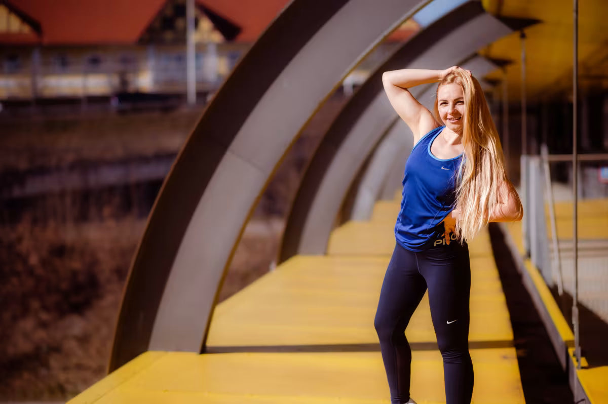 Woman in athletic wear posing on a yellow platform with blurred background